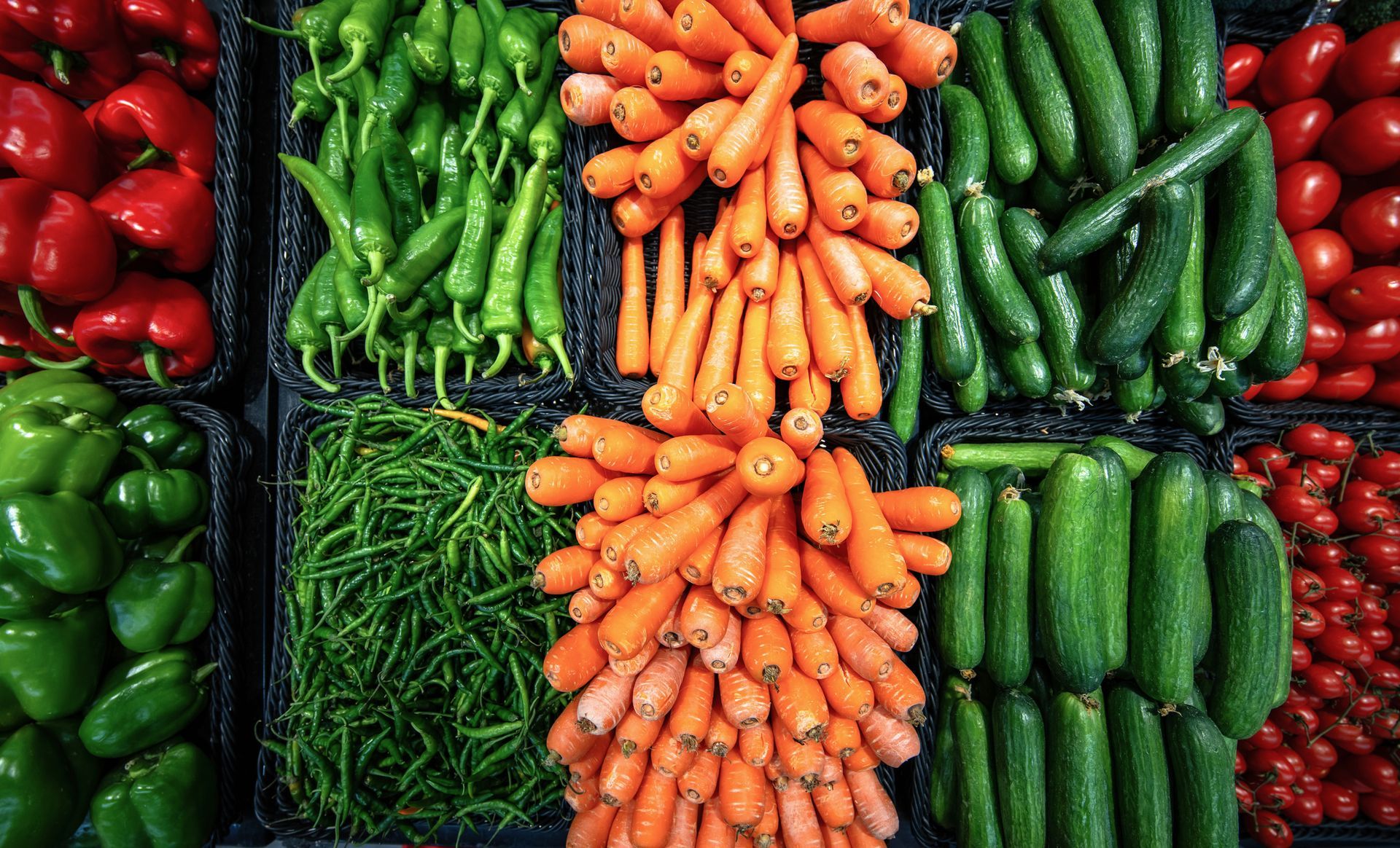 Un mucchio di verdure diverse tra cui carote, cetrioli, peperoni e pomodori