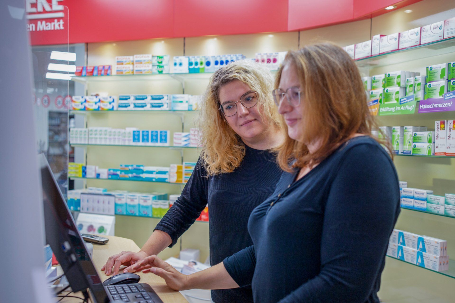 Zwei Frauen schauen in einer Apotheke auf einen Computerbildschirm.