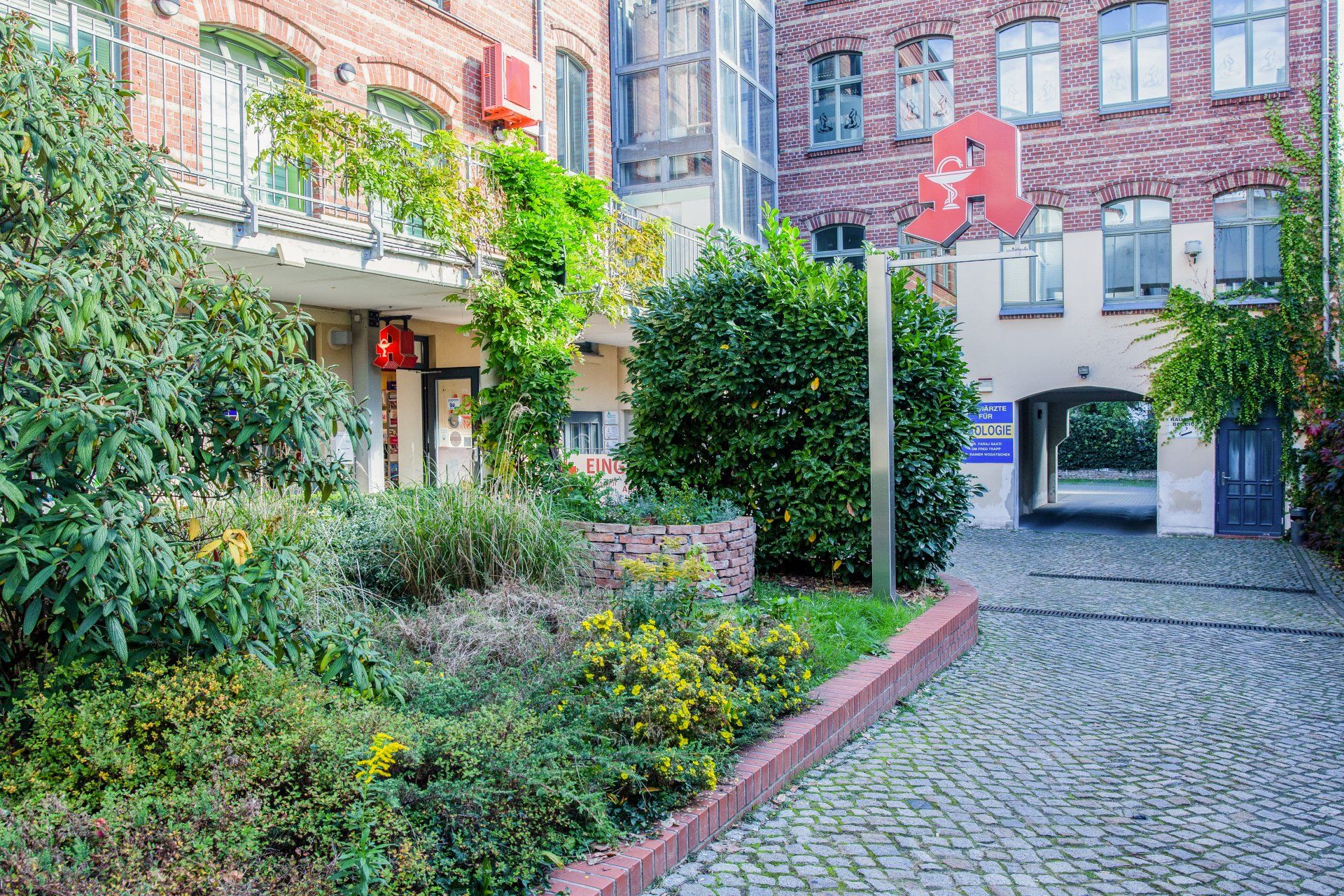 Ein Backsteingebäude mit einem Garten davor.