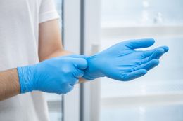 Person putting on blue latex gloves.