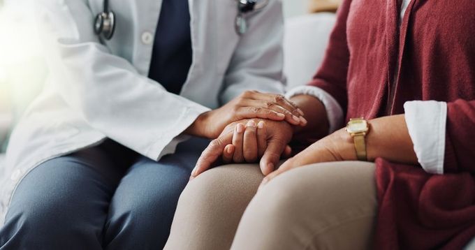 Doctor holding patient's hand for comfort, indoors.