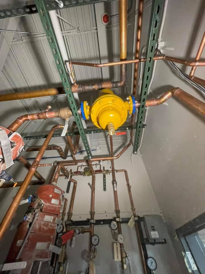 Ceiling-mounted yellow industrial valve and copper pipes in a mechanical room