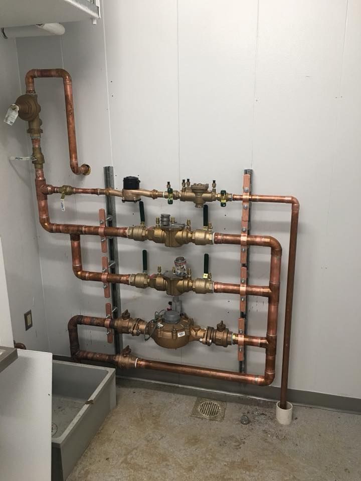 Copper plumbing pipes and valves mounted on a white utility room wall. Copper plumbing pipes and valves mounted on a white utility room wall.