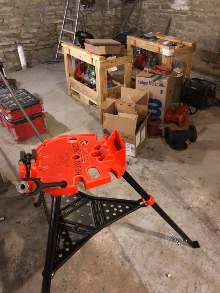Orange mechanic’s creeper on a black stand in a garage with tools and boxes nearby