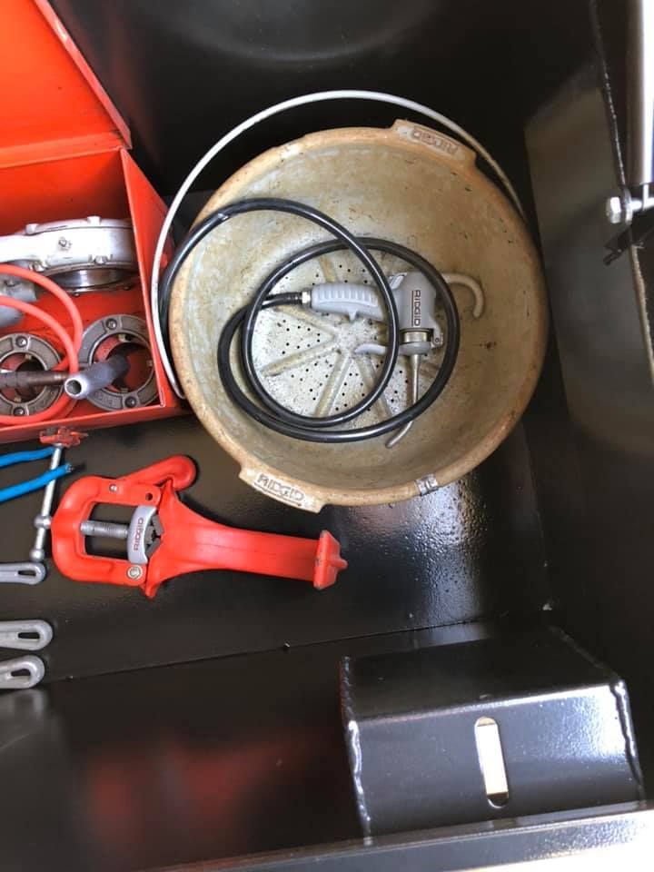 Open toolbox with red hand tools, cables, and a metal bowl-like container.