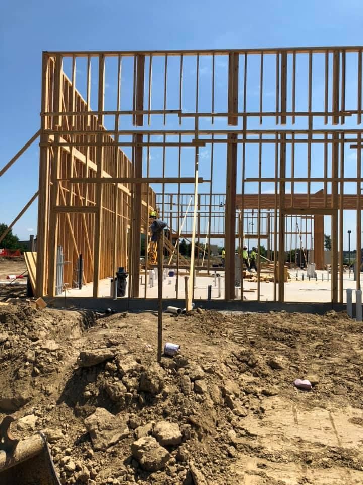Framed wooden building under construction on a dirt lot under a clear blue sky Framed wooden building under construction on a dirt lot under a clear blue sky