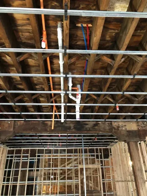 Unfinished room with exposed wooden ceiling joists, metal pipes, and framing during construction. Unfinished room with exposed wooden ceiling joists, metal pipes, and framing during construction.