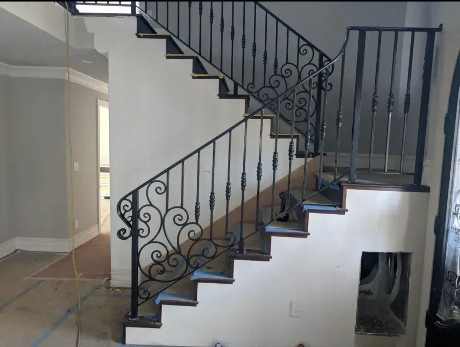 Interior staircase with dark wrought-iron railing in a white-walled home