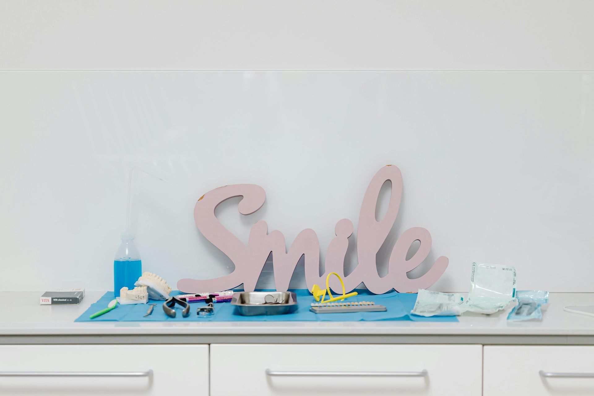 Decorative shelf with pink “Smile” sign, blue candles, and glass jars on a white cabinet