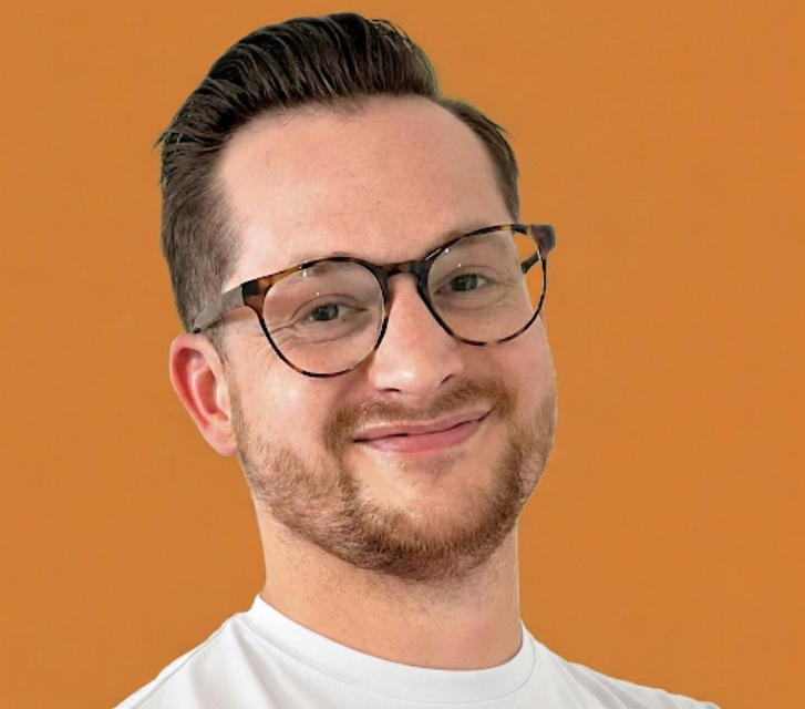 Portrait of a smiling person wearing glasses and a white shirt against an orange background