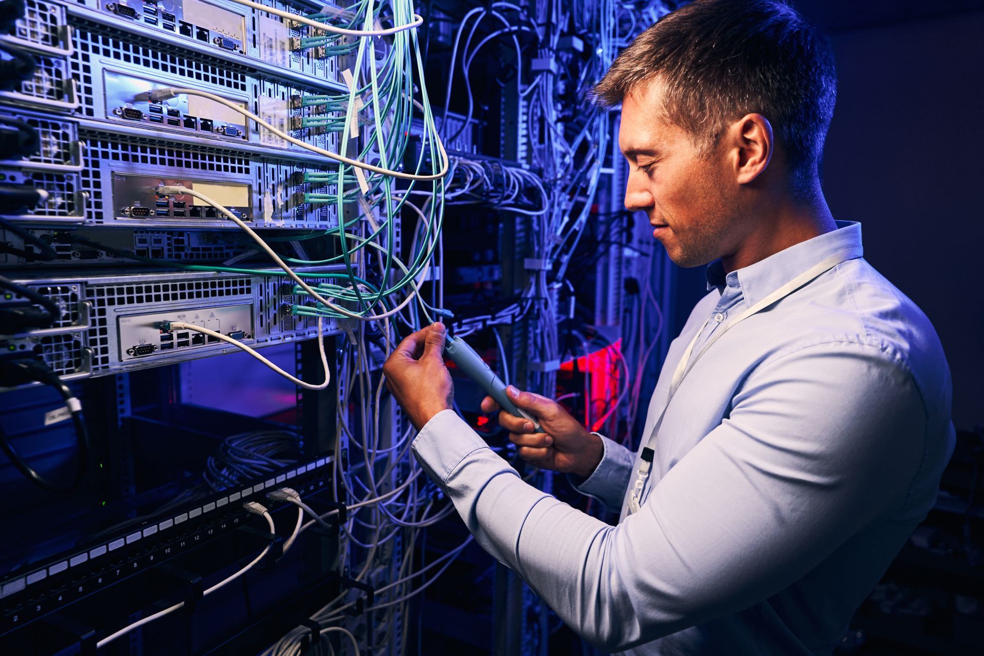 Focused data center employee checking cabling infrastructure. Focused data center employee checking cabling infrastructure.