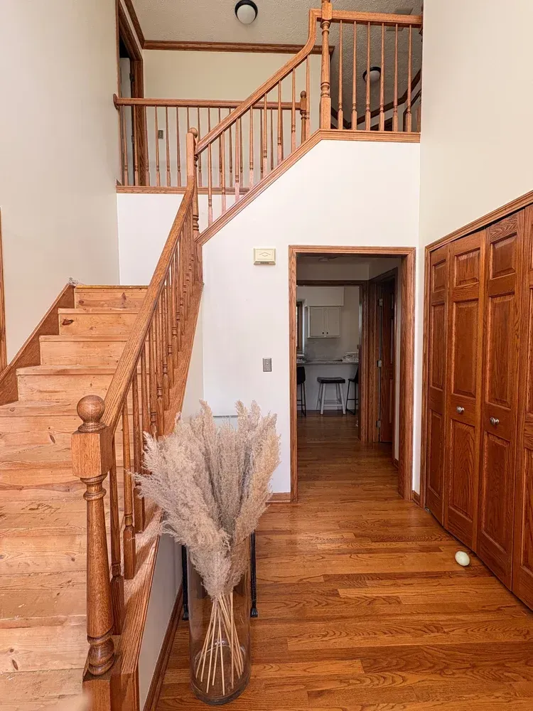 Wooden staircase in a home entryway, leading to an upper level. Hardwood floors, light walls