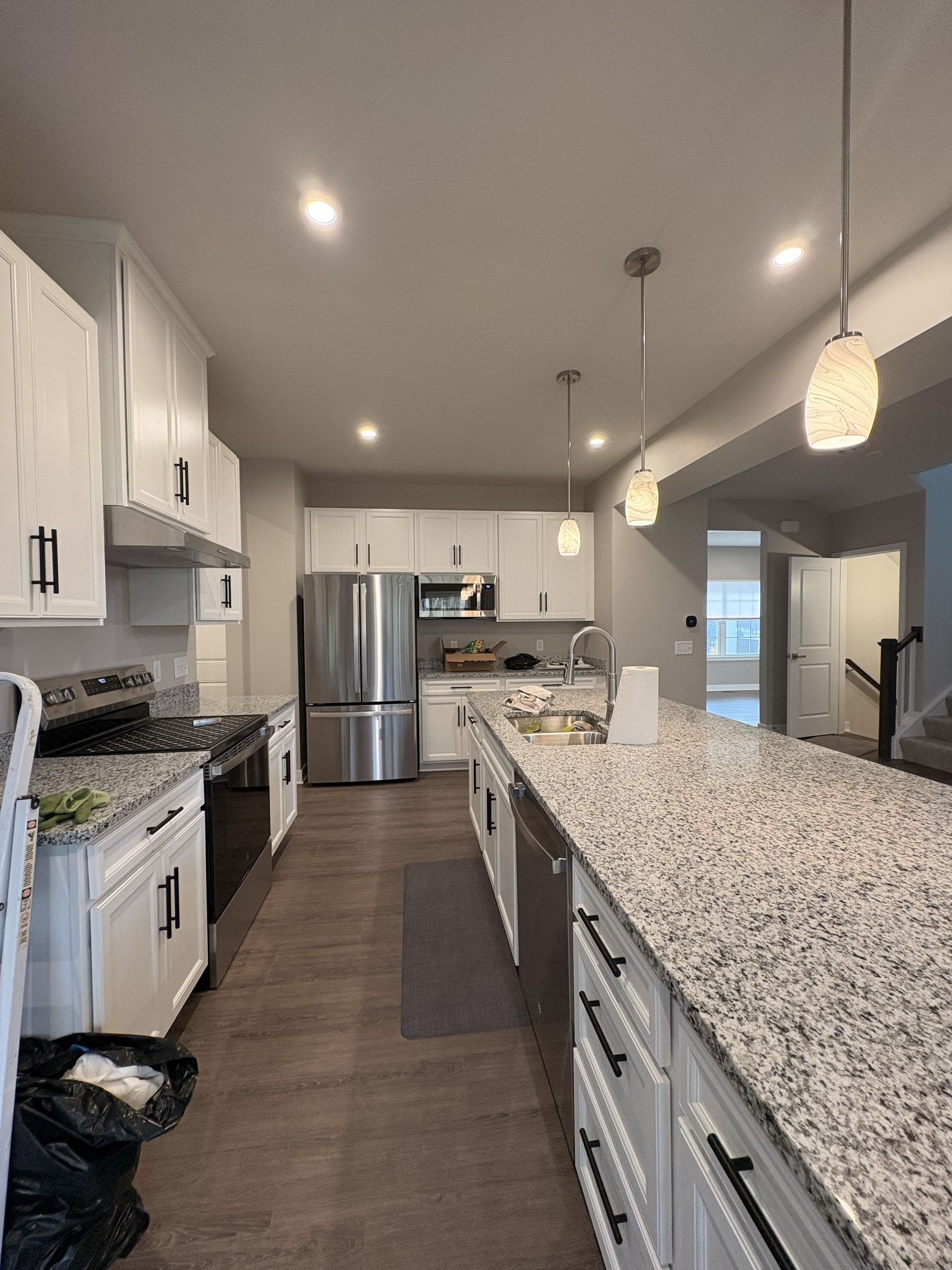 Bright white kitchen with granite island and stainless steel appliances.