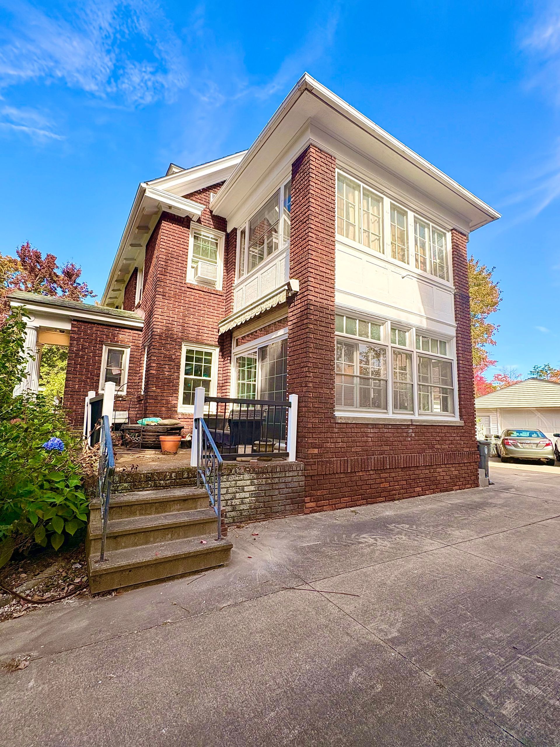 Red brick house with white trim and multi-pane windows under a clear blue sky.