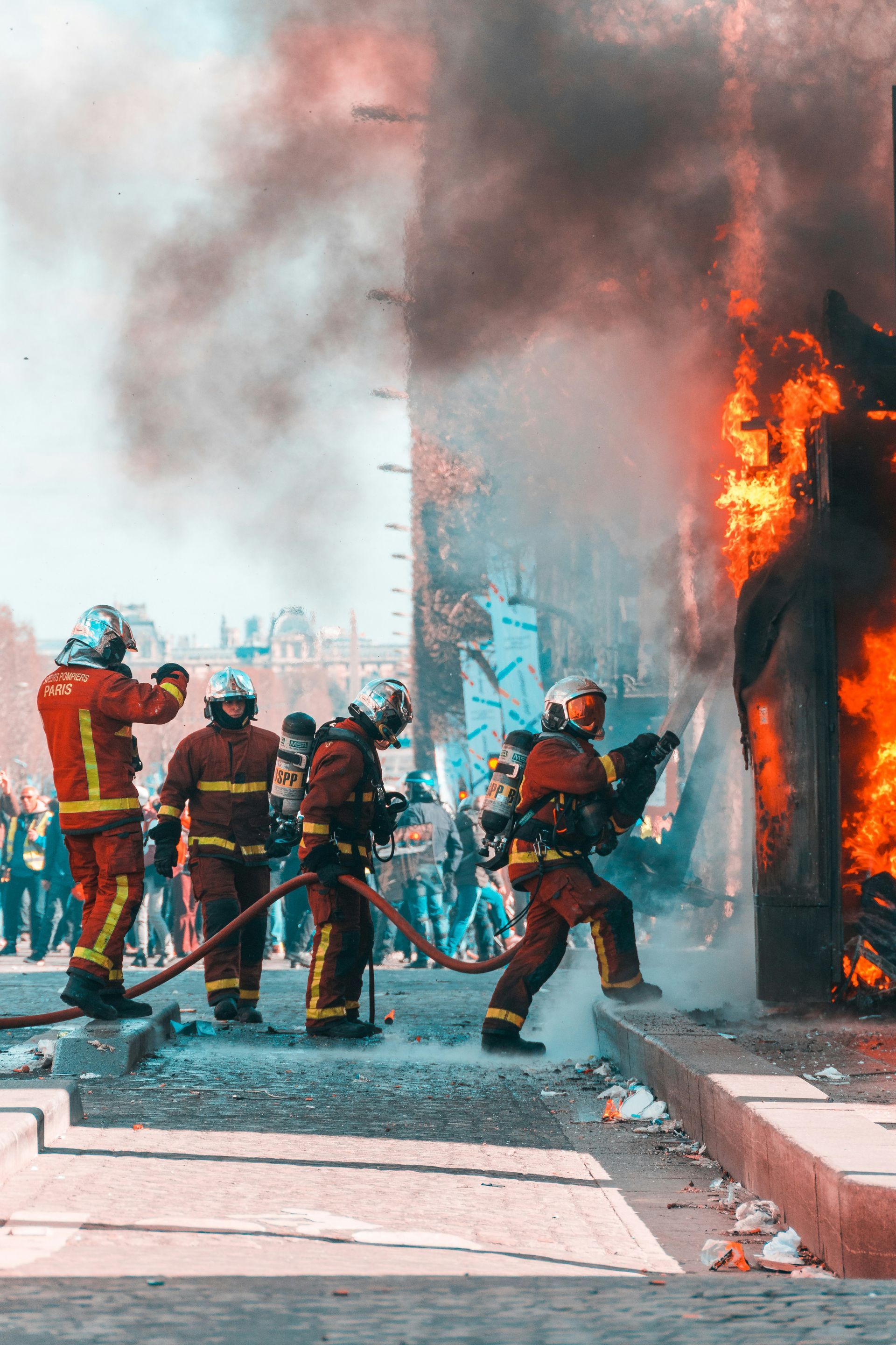 A group of firefighters are fighting a fire with a hose.