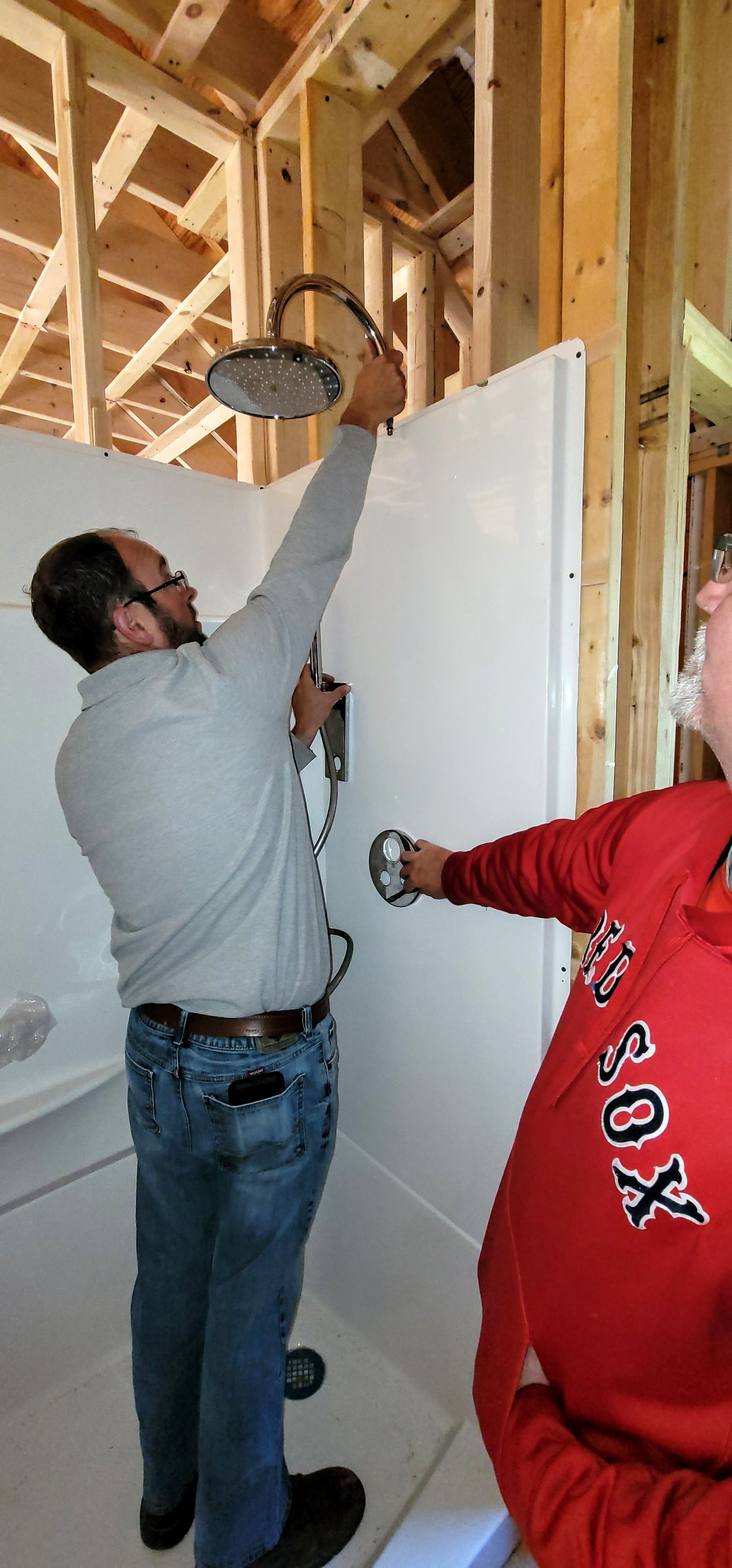 A man is installing a shower head in a bathroom.