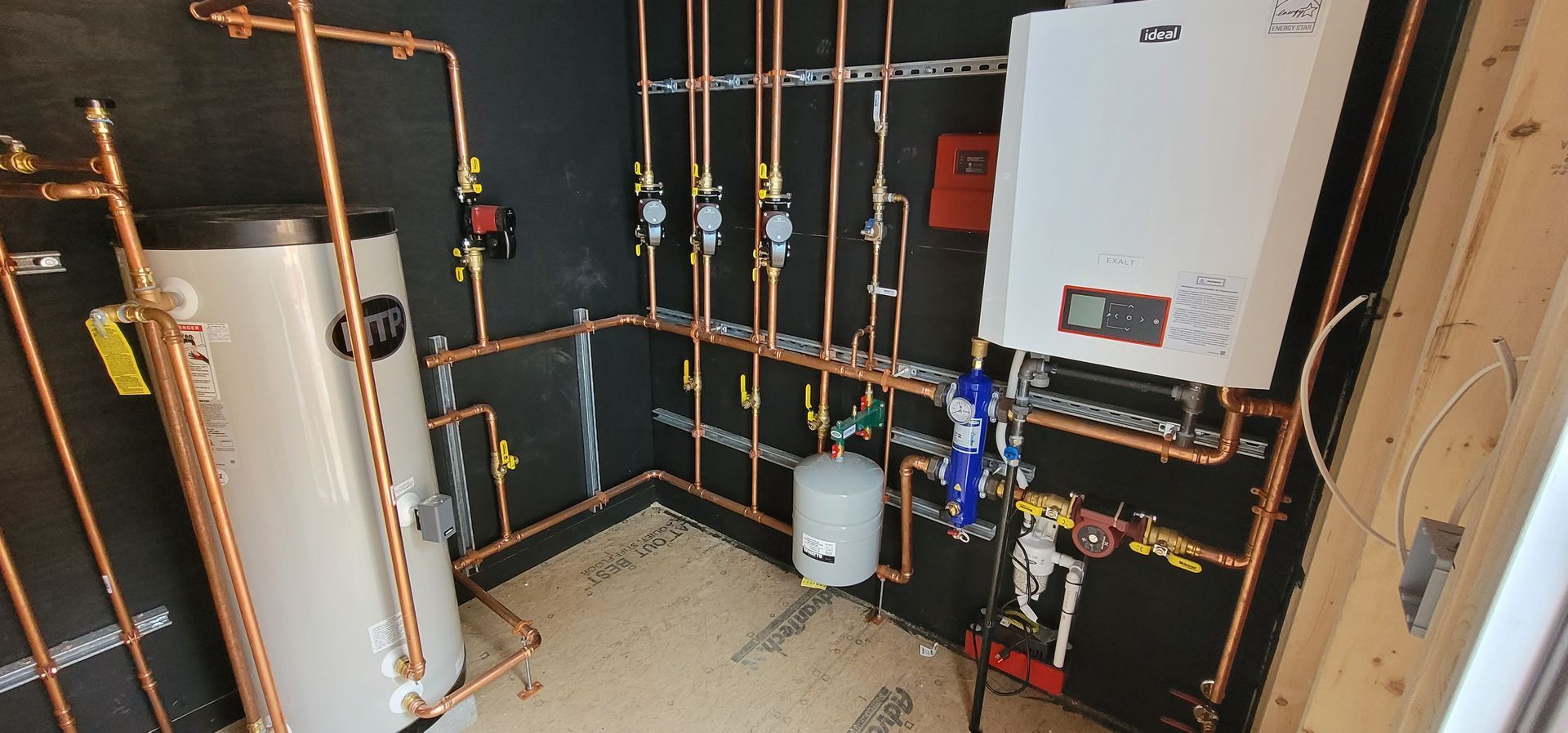 A room with a lot of pipes and a boiler in it.