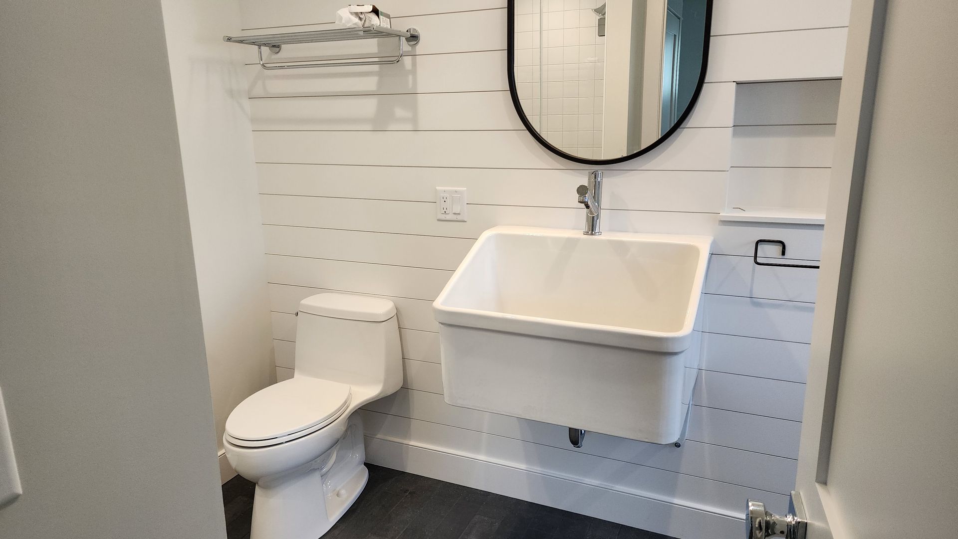 A bathroom with a toilet , sink and mirror.
