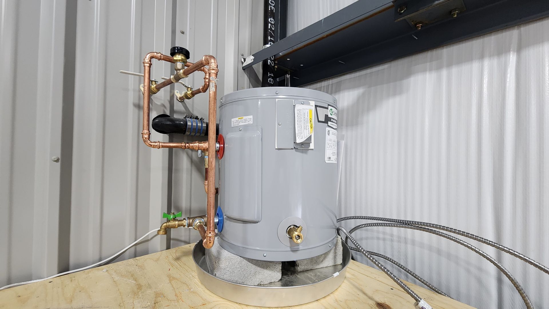 A water heater is sitting on top of a wooden floor in a building.