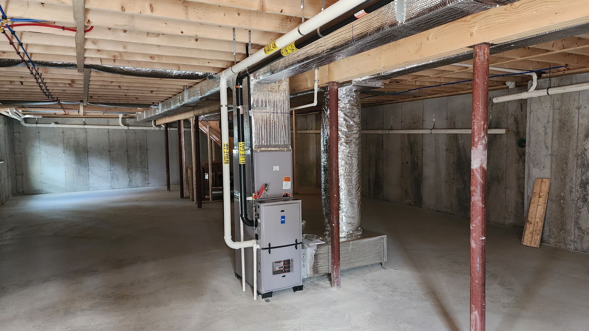 An empty basement with a furnace and pipes.