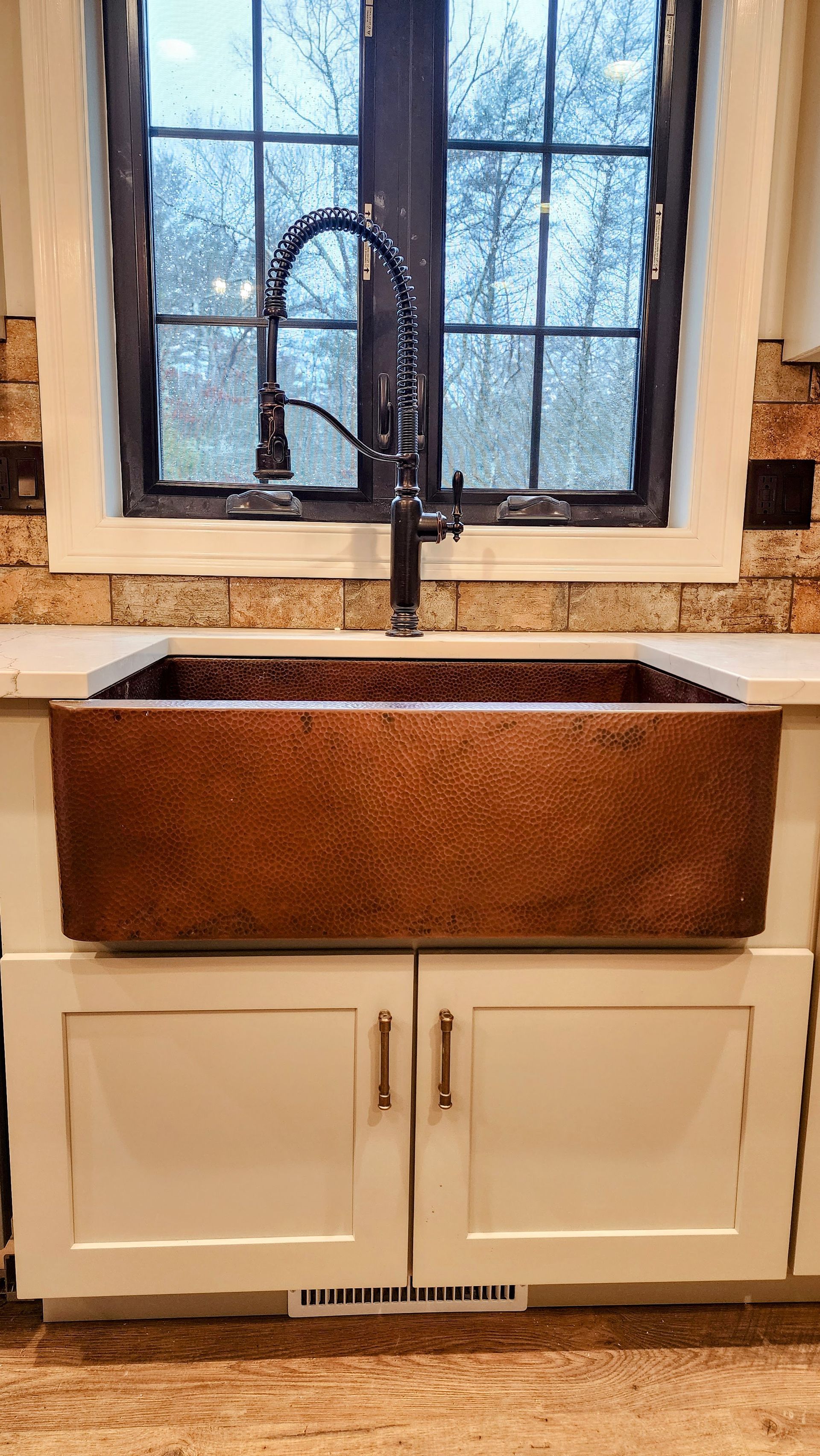 A kitchen sink with a faucet and a window in the background.