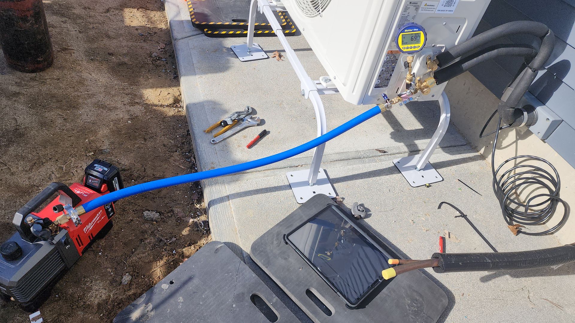 A blue hose is connected to a compressor on a concrete surface.