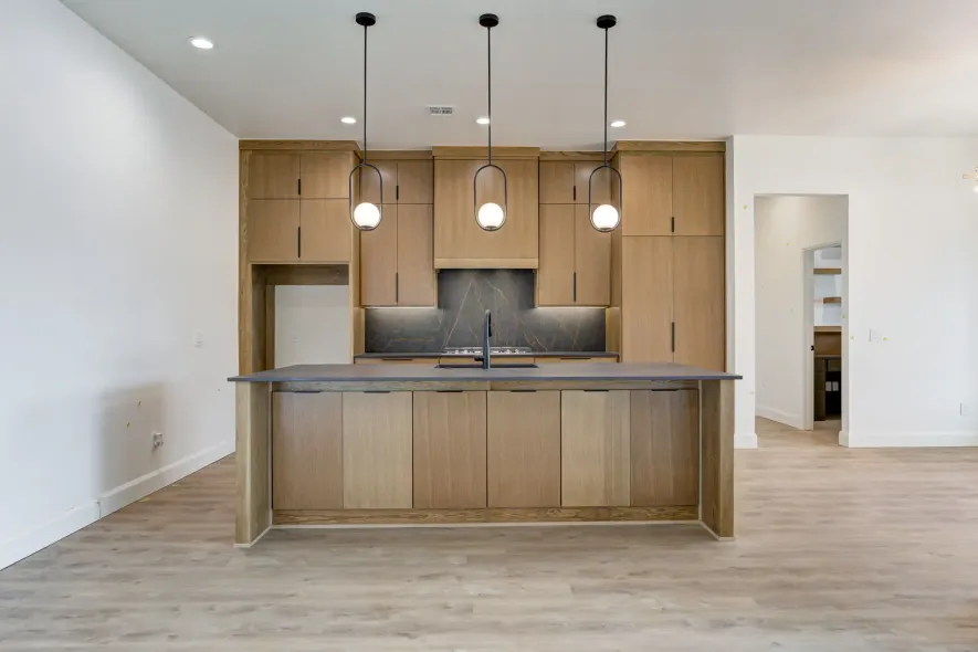 Modern kitchen with wood cabinets, center island, pendant lights, and light wood flooring