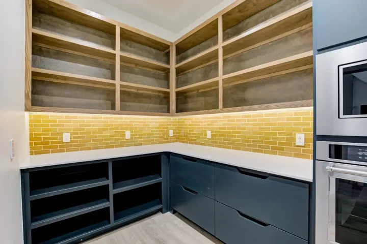 Modern kitchen corner with empty shelves, yellow tile backsplash, and dark lower cabinets
