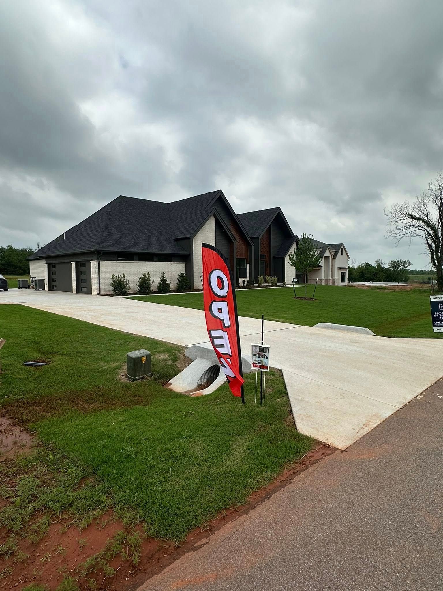 Modern house with a red real estate sign in front, on a cloudy day