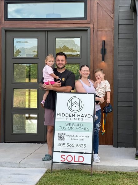 Family standing outside a house with a real estate sign that says “SOLD”