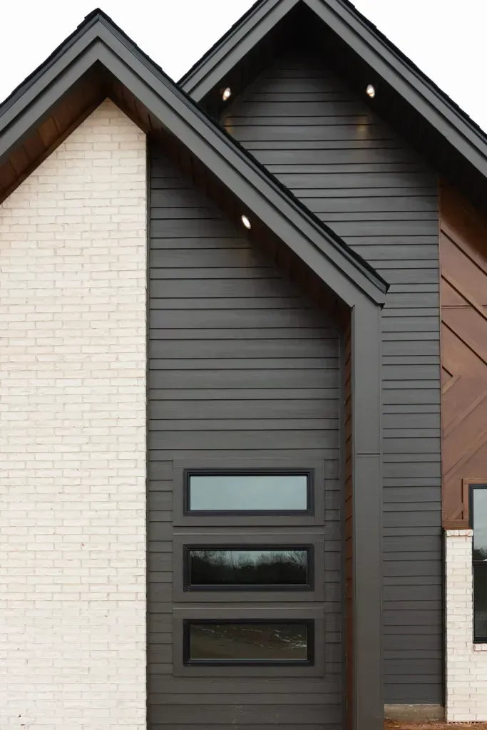 Modern house facade with dark gray siding, white brick, and narrow horizontal windows