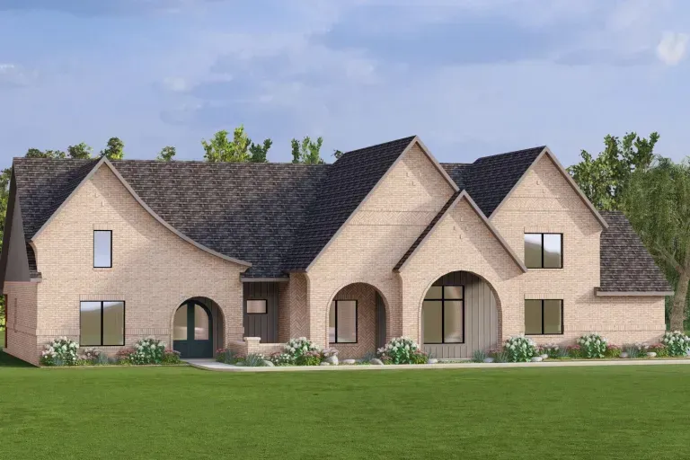 Large tan brick suburban house with dark roof, arched windows, and a green lawn