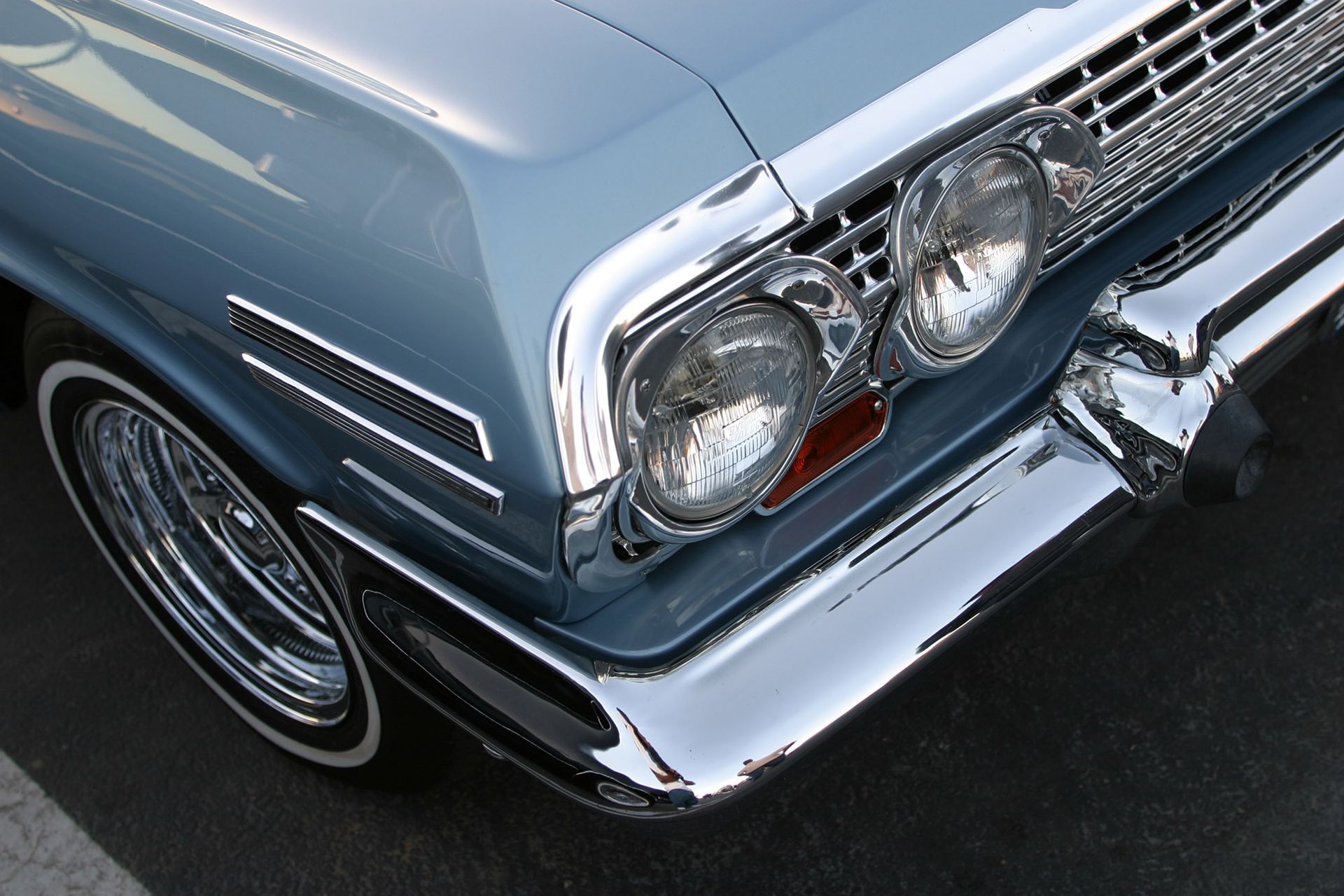 Light blue classic car, chrome detailing on front, white-walled tires.