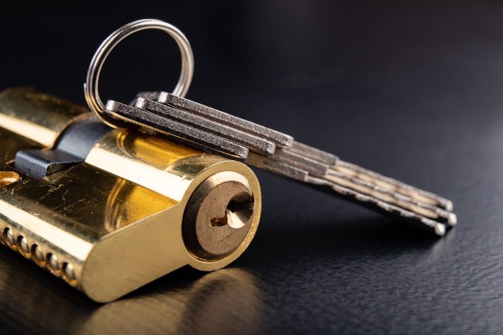 Close-Up of A Gold Door Lock with Keys on A Dark Surface — NORTHCOAST LOCKSMITHS & SECURITY In Forster, NSW