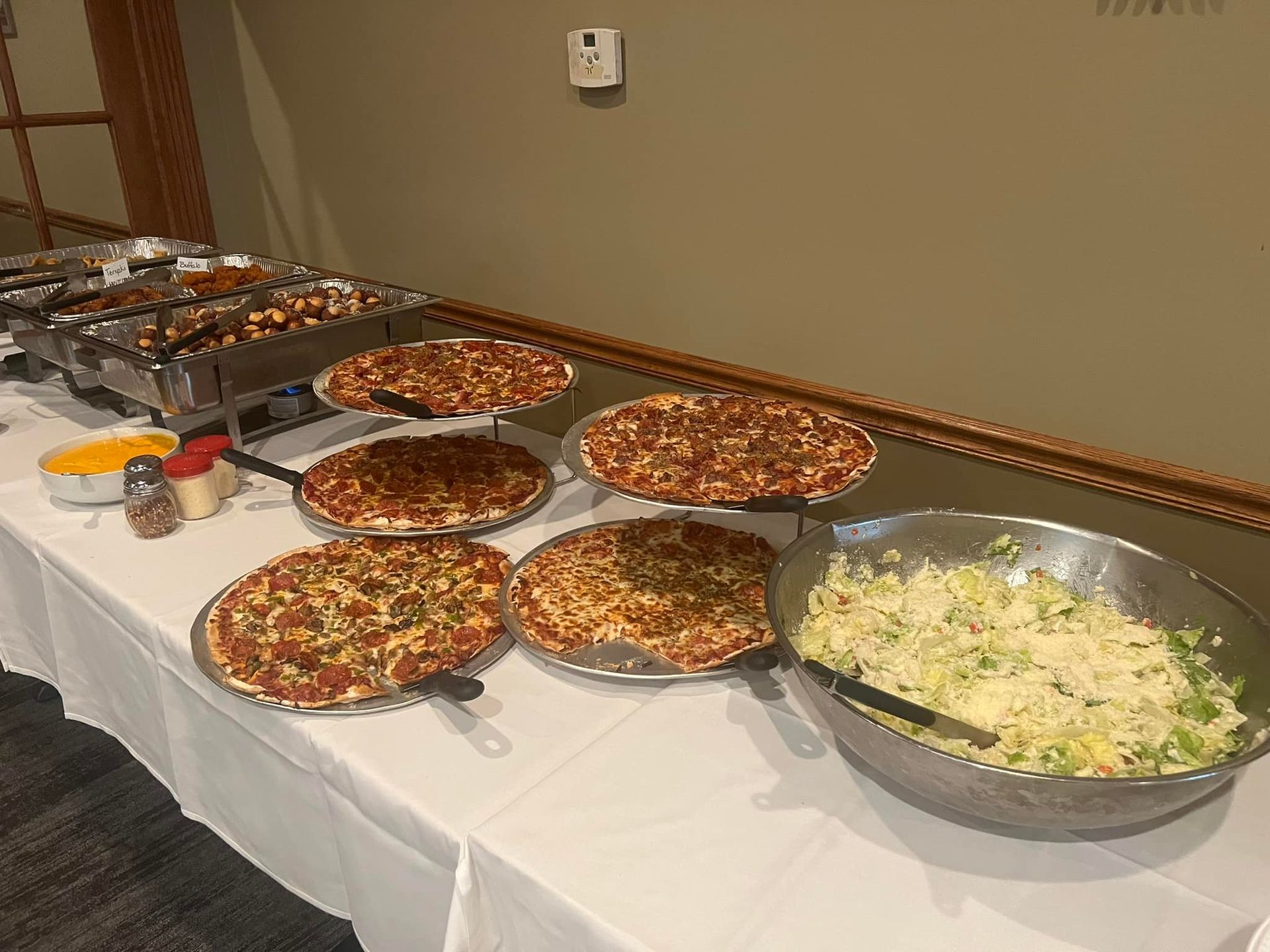 A table topped with plates of pizza and a bowl of coleslaw.