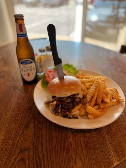 A hamburger and french fries on a plate next to a bottle of beer.