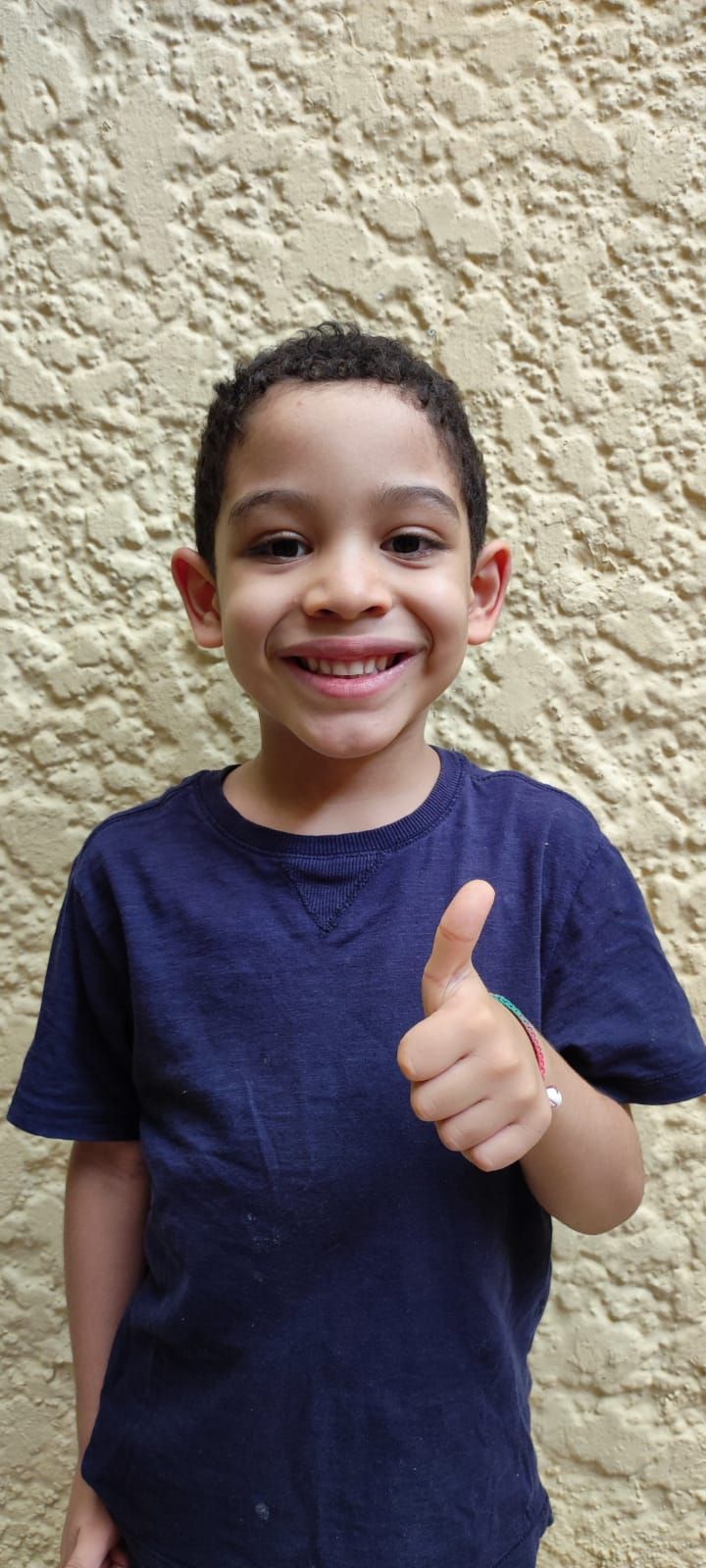 Persona joven con una camisa azul haciendo un gesto de pulgar hacia arriba