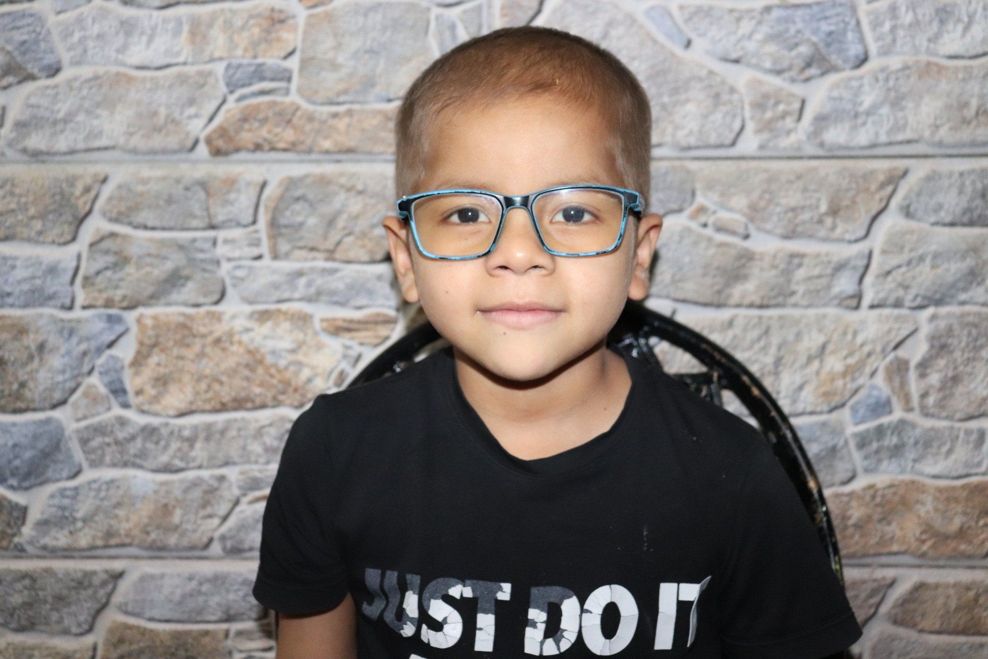Un niño con gafas y una camiseta negra que dice 
