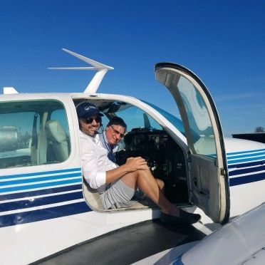 Two men are sitting in the cockpit of a small plane
