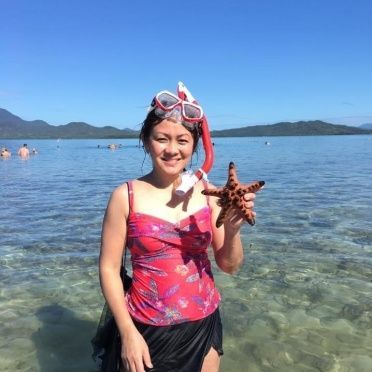 A woman is holding a starfish in the water