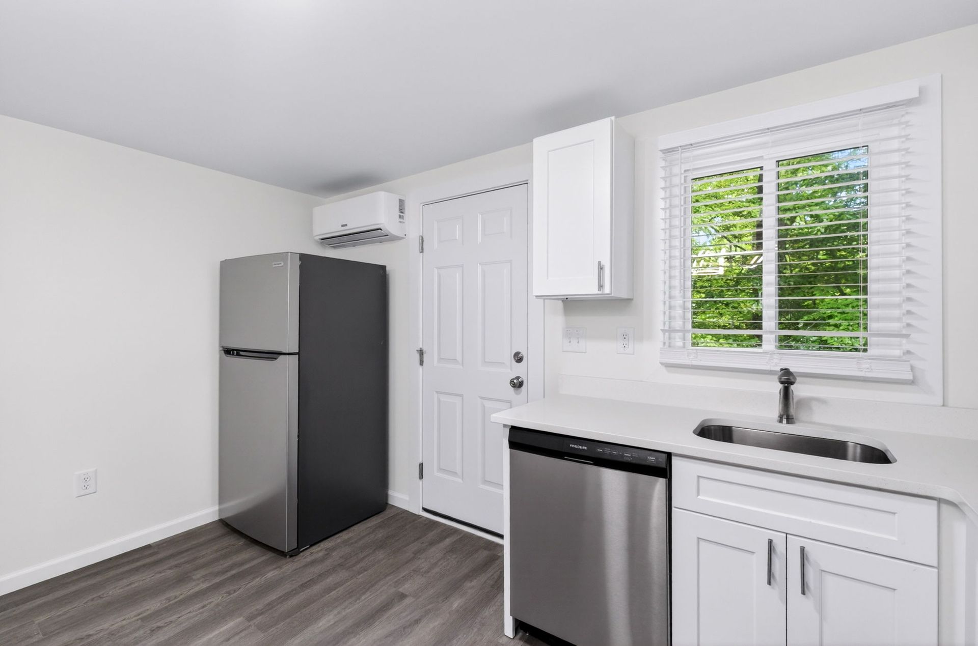Bright white kitchen with stainless appliances, gray floor, and window above the sink