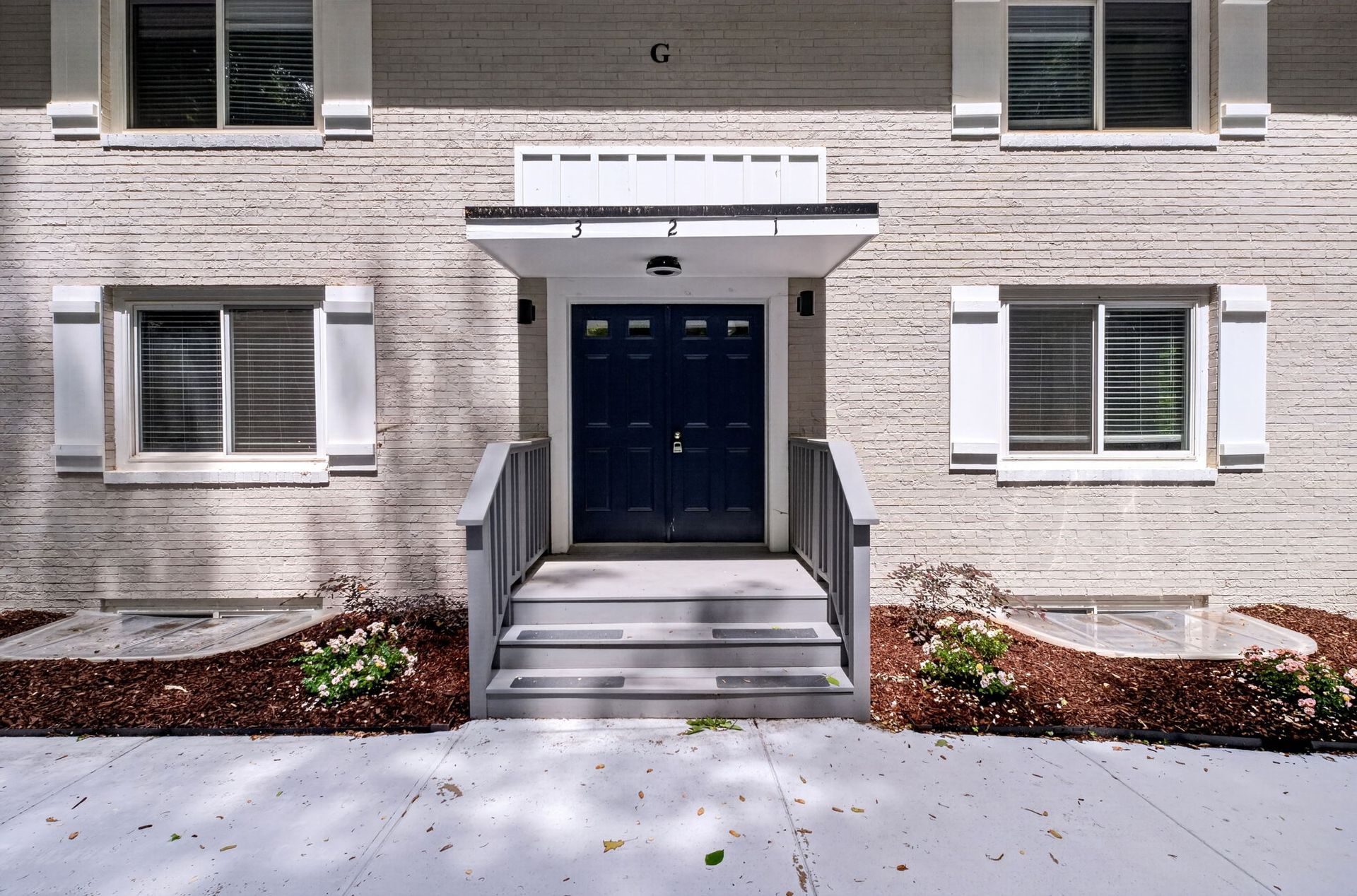 Apartment building entrance with blue double doors, steps, and white brick facade
