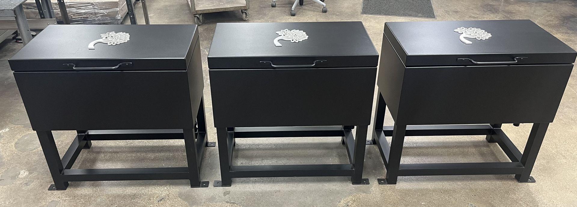Three black metal storage bins on metal stands.