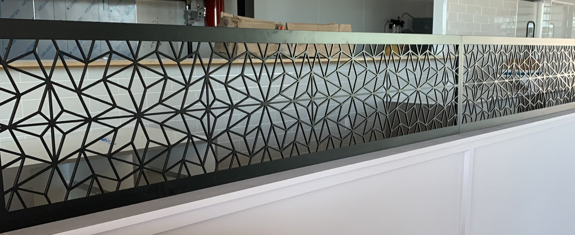 Black metal screen with geometric pattern on white counter.