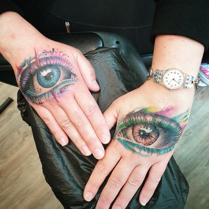 Hände mit bunten Augentattoos 