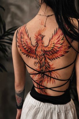 Rückentattoo eines feurigen Phönix mit ausgebreiteten Flügeln auf einer Frau, gestochen von Marco