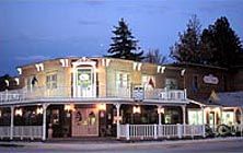 A large building with a porch and trees in the background is lit up at night.