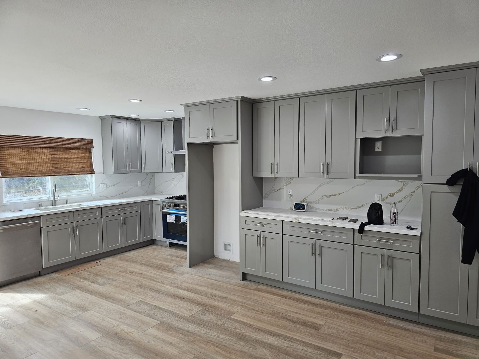 Empty modern kitchen with gray cabinets, white countertops, and light wood flooring