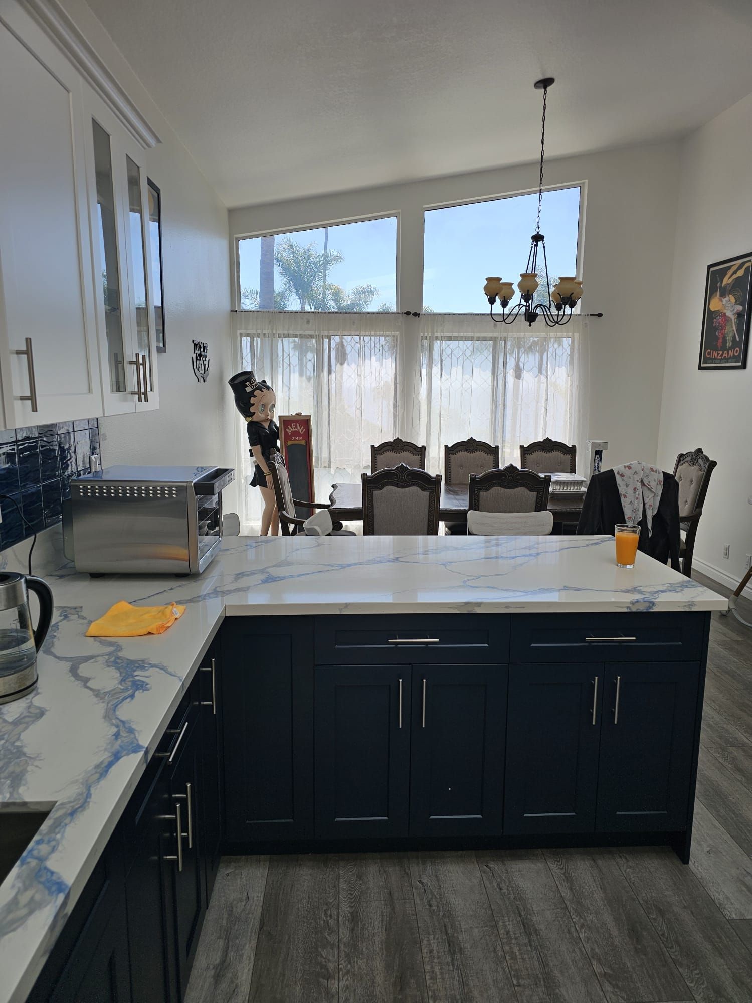 Modern kitchen with white cabinets, dark island, and dining table by bright windows