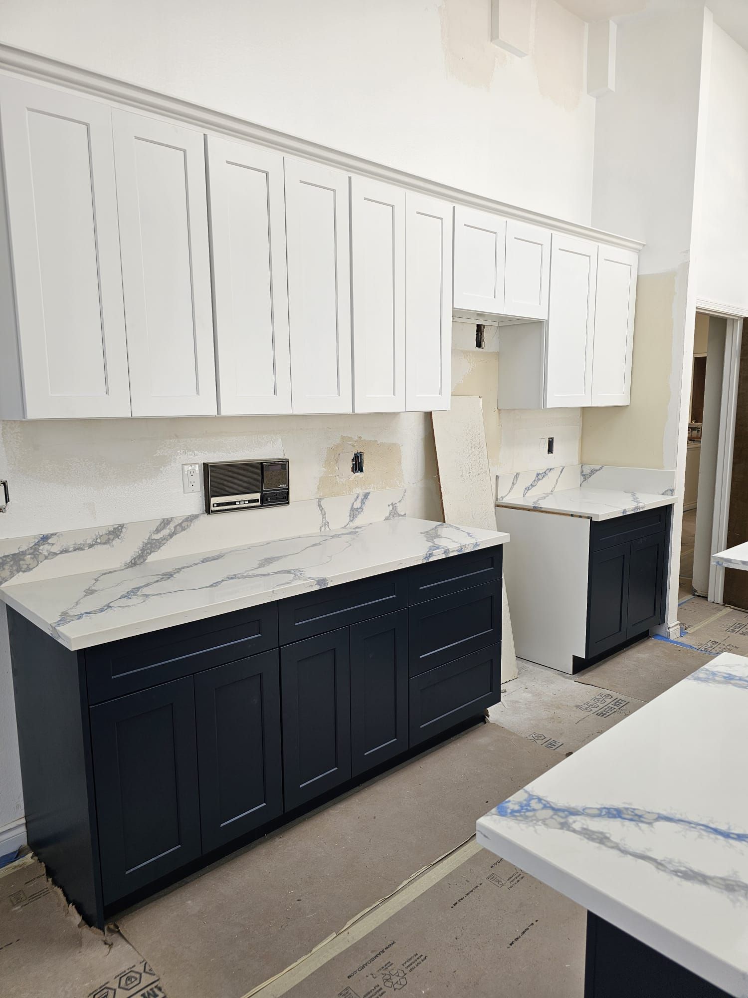 Modern kitchen with white upper cabinets, dark lower cabinets, marble backsplash, and countertop workspace